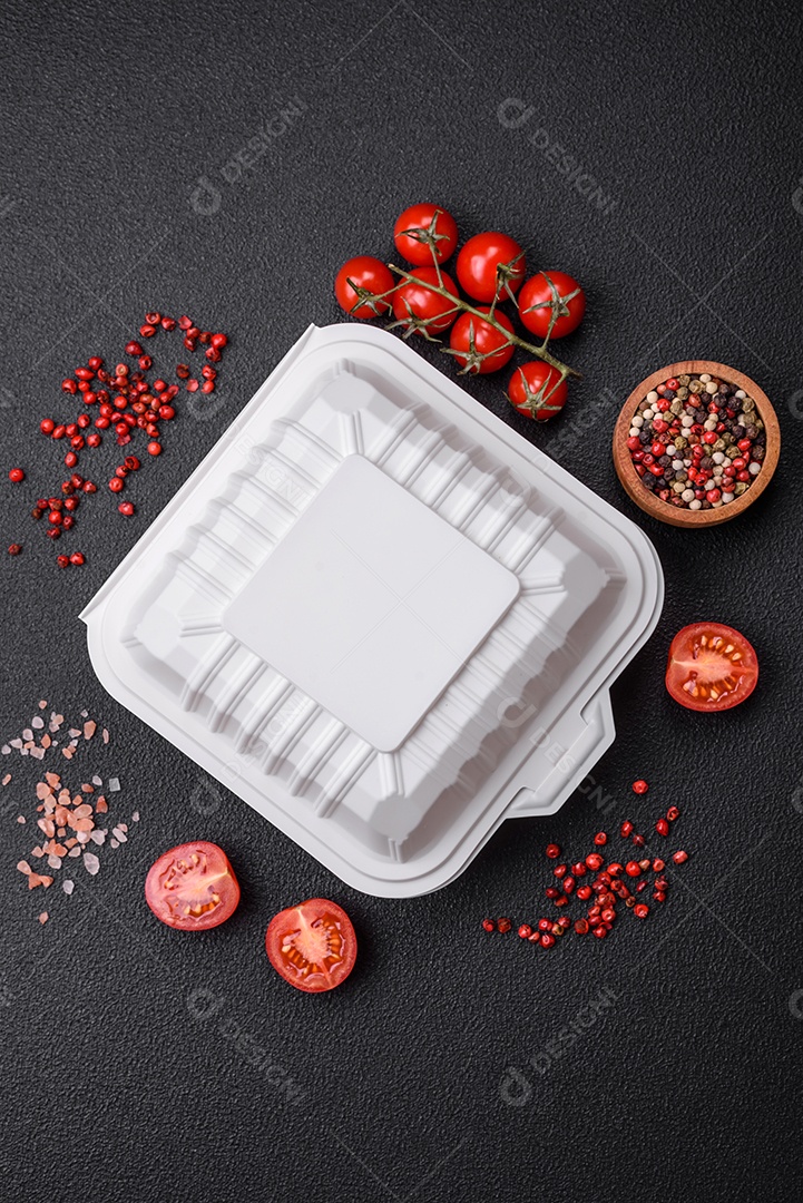 Recipiente quadrado de plástico ou papelão de cor branca para alimentos sobre um fundo escuro de concreto