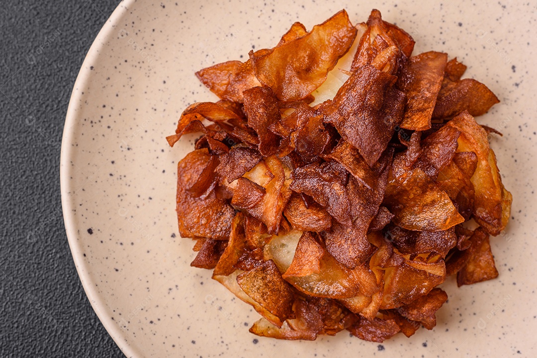 Deliciosas batatas fritas crocantes com sal e especiarias em um fundo escuro de concreto