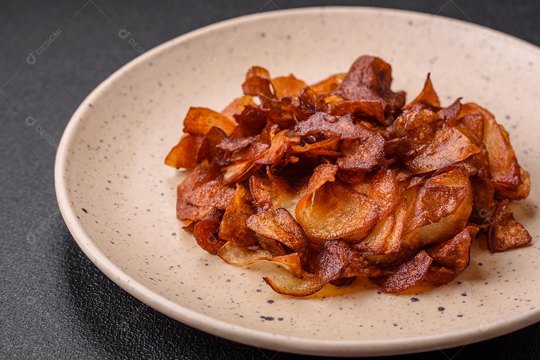 Deliciosas batatas fritas crocantes com sal e especiarias em um fundo escuro de concreto