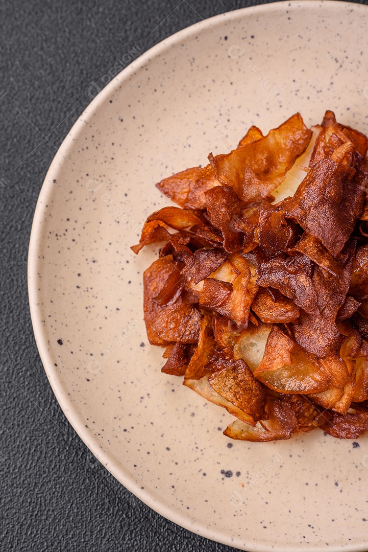 Deliciosas batatas fritas crocantes com sal e especiarias em um fundo escuro de concreto