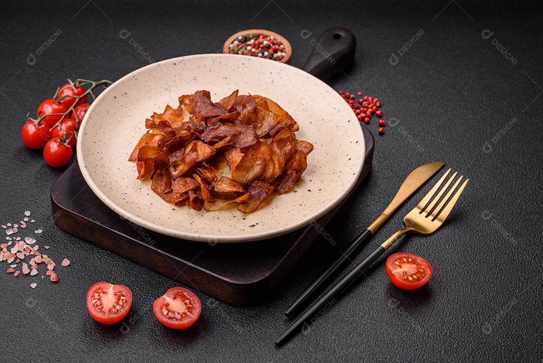 Deliciosas batatas fritas crocantes com sal e especiarias em um fundo escuro de concreto