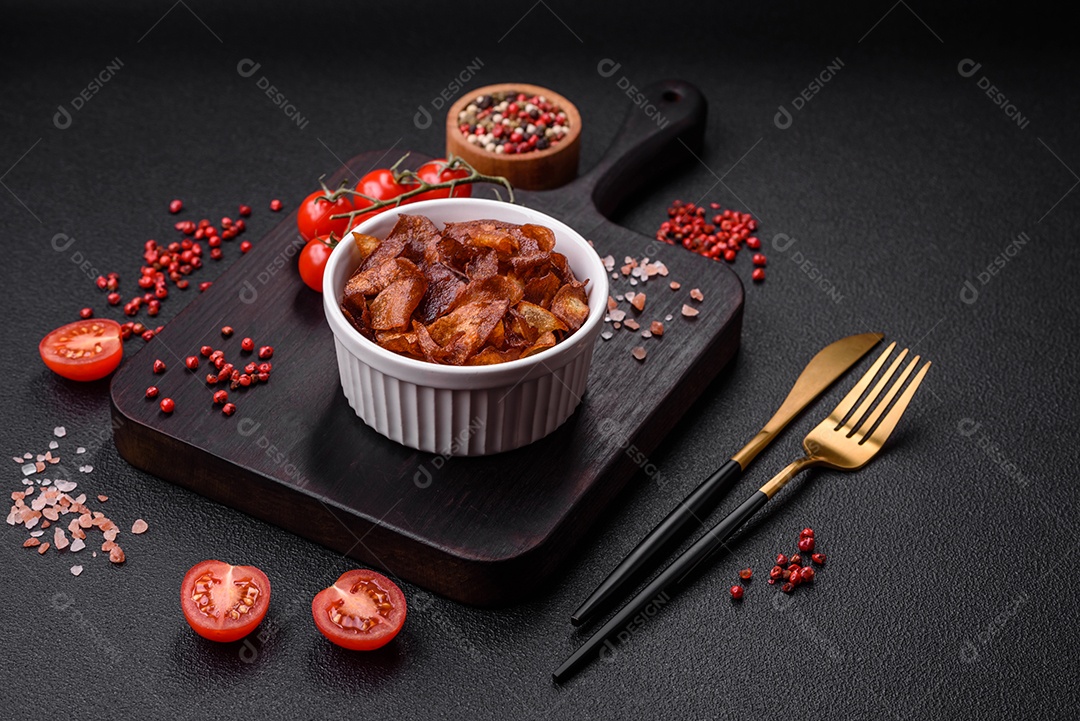 Deliciosas batatas fritas crocantes com sal e especiarias em um fundo escuro de concreto