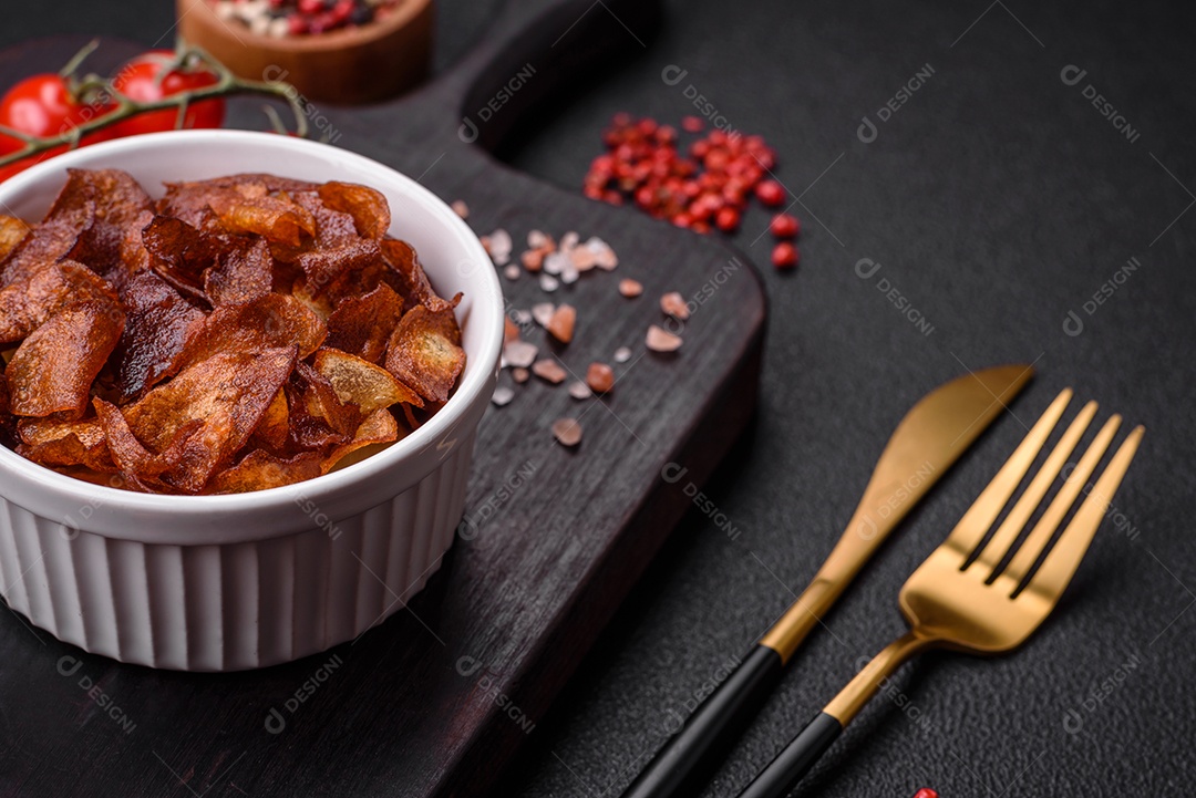 Deliciosas batatas fritas crocantes com sal e especiarias em um fundo escuro de concreto