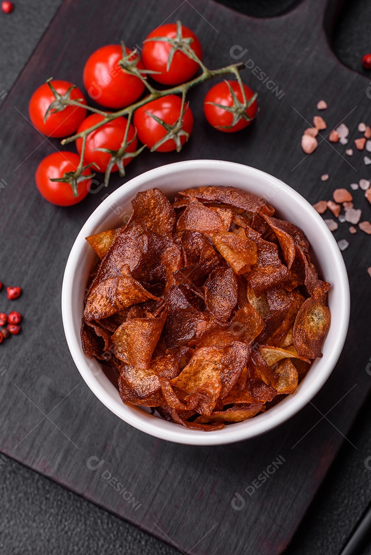 Deliciosas batatas fritas crocantes com sal e especiarias em um fundo escuro de concreto