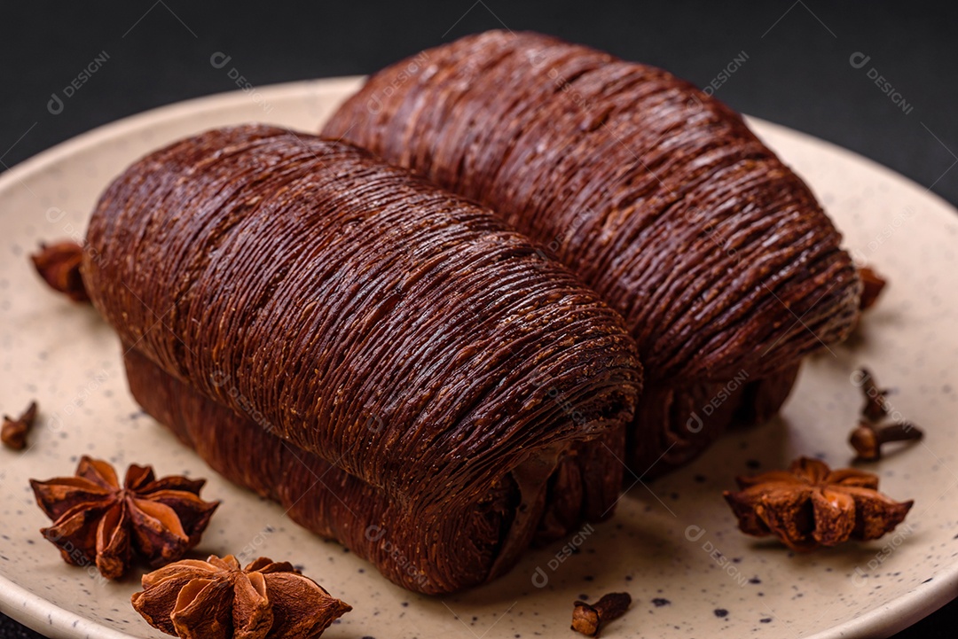 Deliciosa massa folhada crocante e doce com recheio de chocolate sobre um fundo escuro de concreto