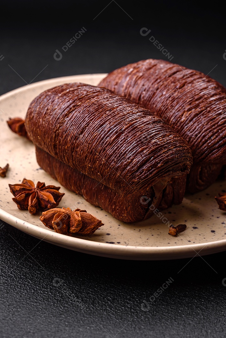 Deliciosa massa folhada crocante e doce com recheio de chocolate sobre um fundo escuro de concreto