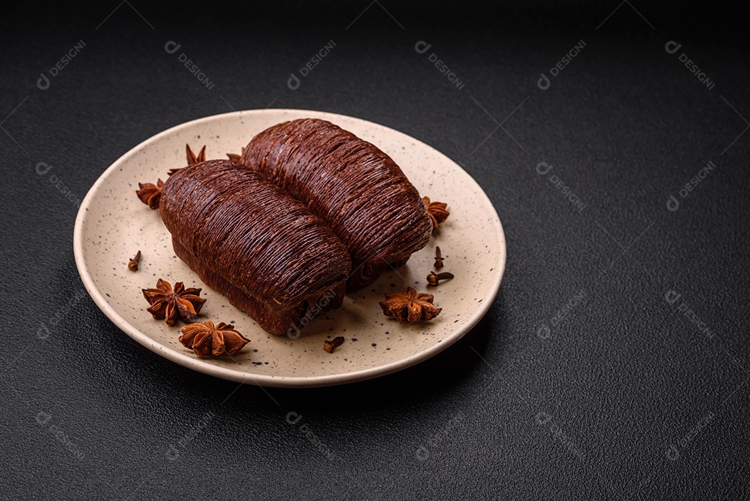 Deliciosa massa folhada crocante e doce com recheio de chocolate sobre um fundo escuro de concreto