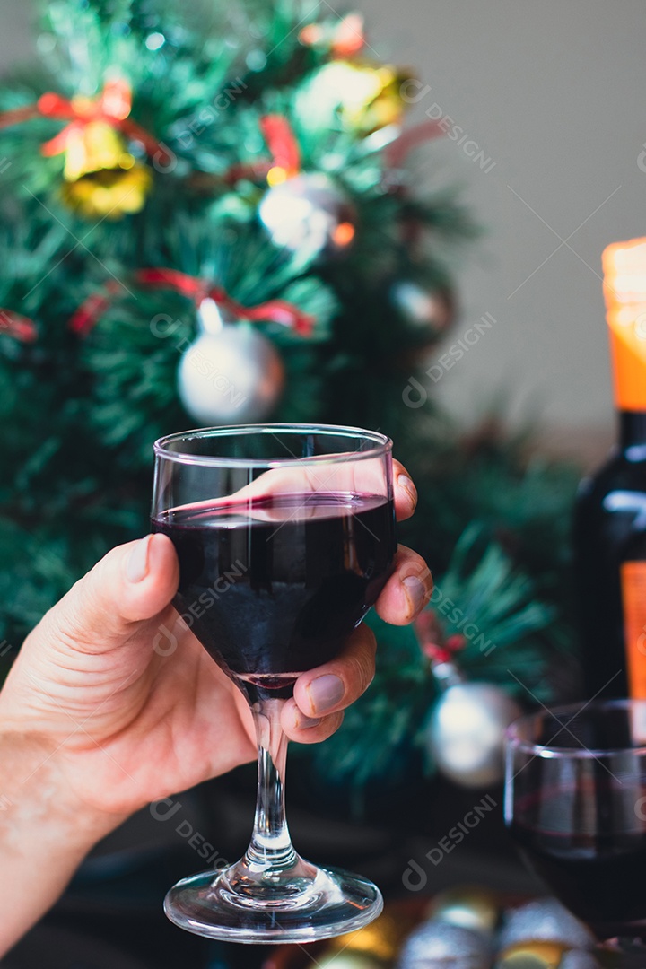 Segurando uma taça de vinho com árvore de Natal no fundo do quintal