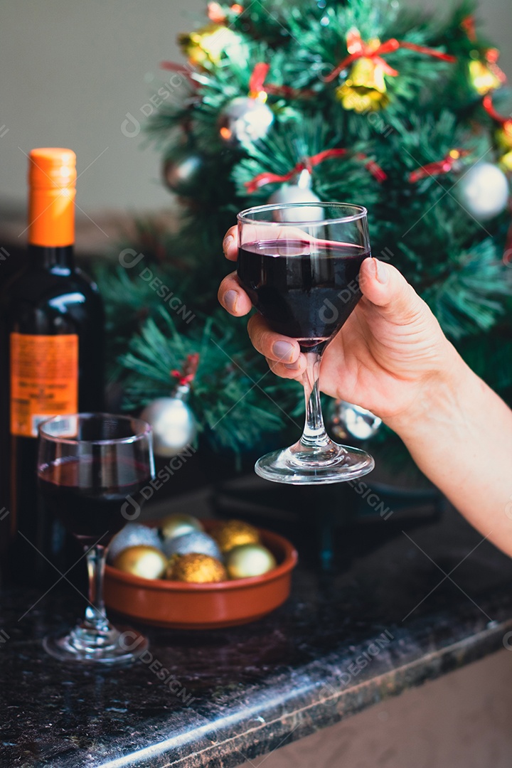 Segurando uma taça de vinho com árvore de Natal no fundo do quintal