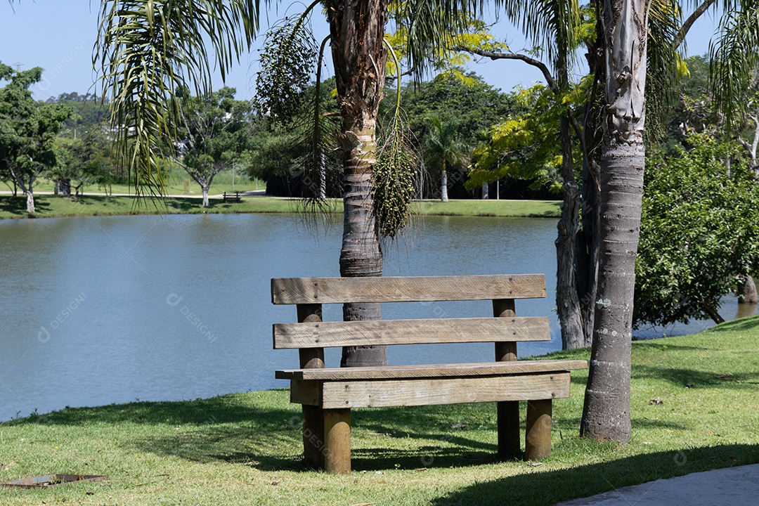 Banquinho de madeira em uma praça com fundo de um lago.