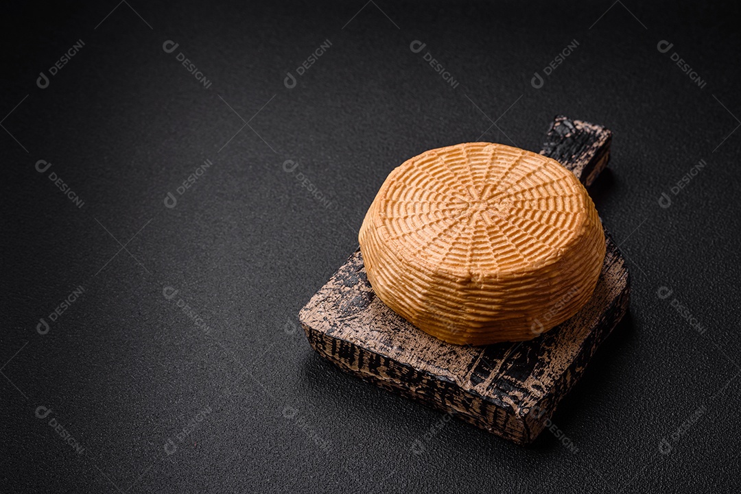 Delicioso queijo artesanal feito de leite de vaca ou cabra sobre um fundo escuro de concreto