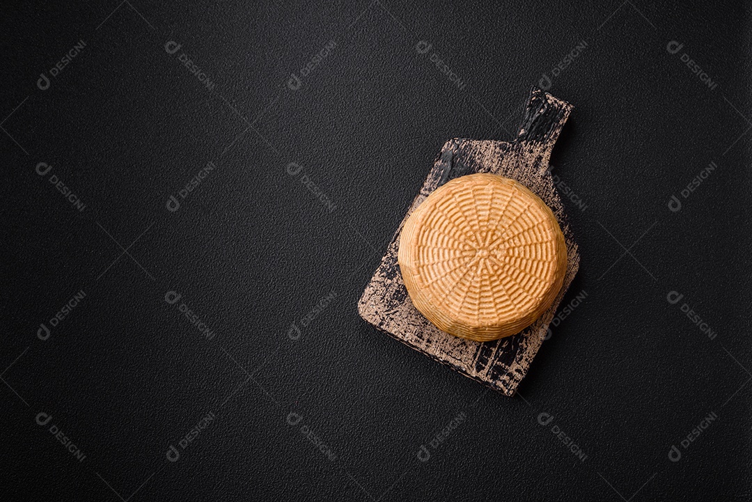Delicioso queijo artesanal feito de leite de vaca ou cabra sobre um fundo escuro de concreto