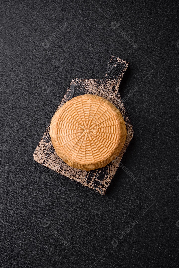 Delicioso queijo artesanal feito de leite de vaca ou cabra sobre um fundo escuro de concreto