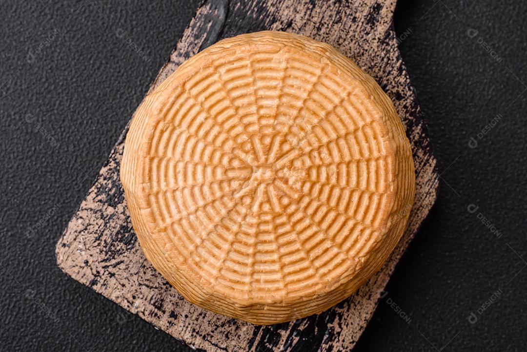 Delicioso queijo artesanal feito de leite de vaca ou cabra sobre um fundo escuro de concreto