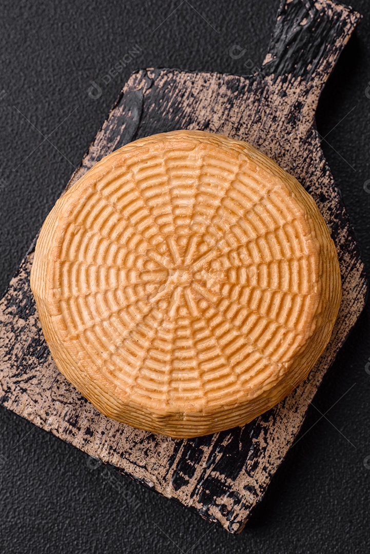 Delicioso queijo artesanal feito de leite de vaca ou cabra sobre um fundo escuro de concreto