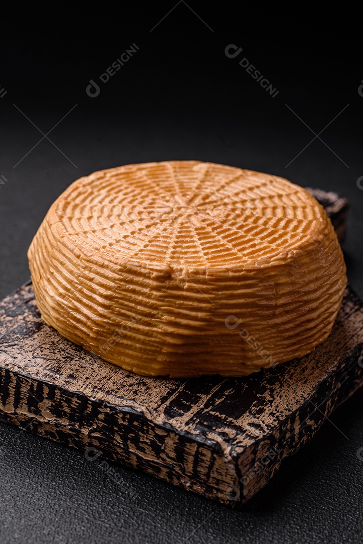 Delicioso queijo artesanal feito de leite de vaca ou cabra sobre um fundo escuro de concreto