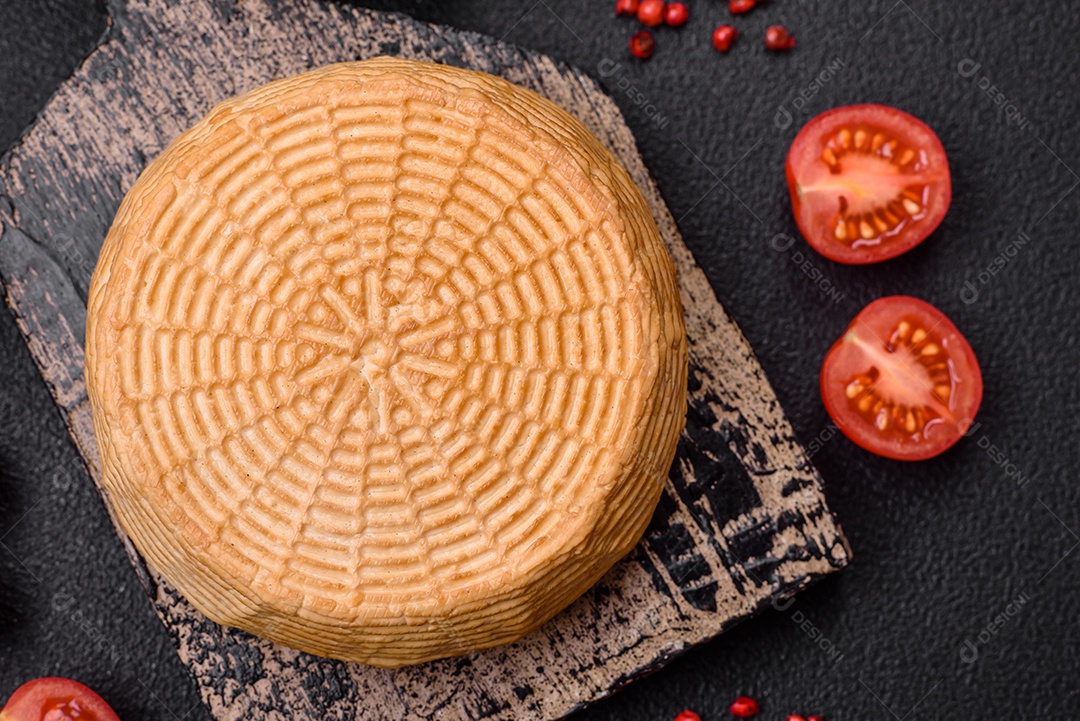 Delicioso queijo artesanal feito de leite de vaca ou cabra sobre um fundo escuro de concreto