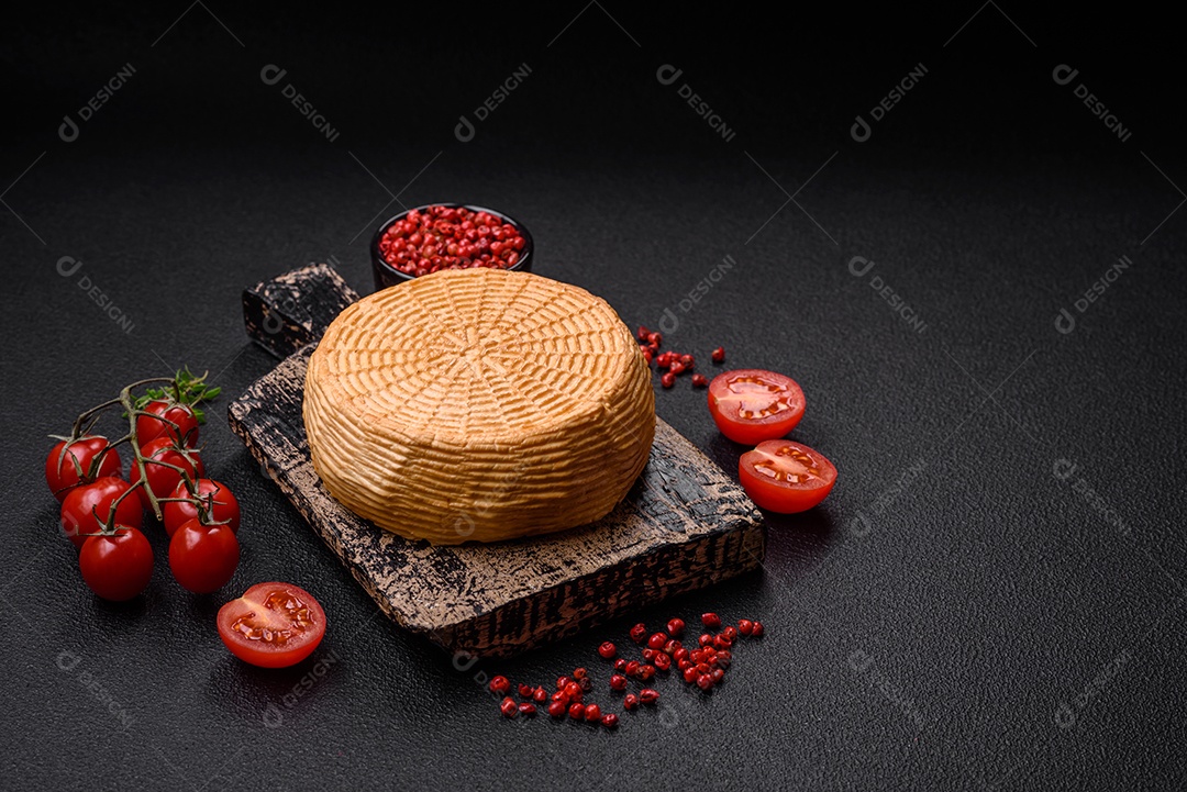 Delicioso queijo artesanal feito de leite de vaca ou cabra sobre um fundo escuro de concreto