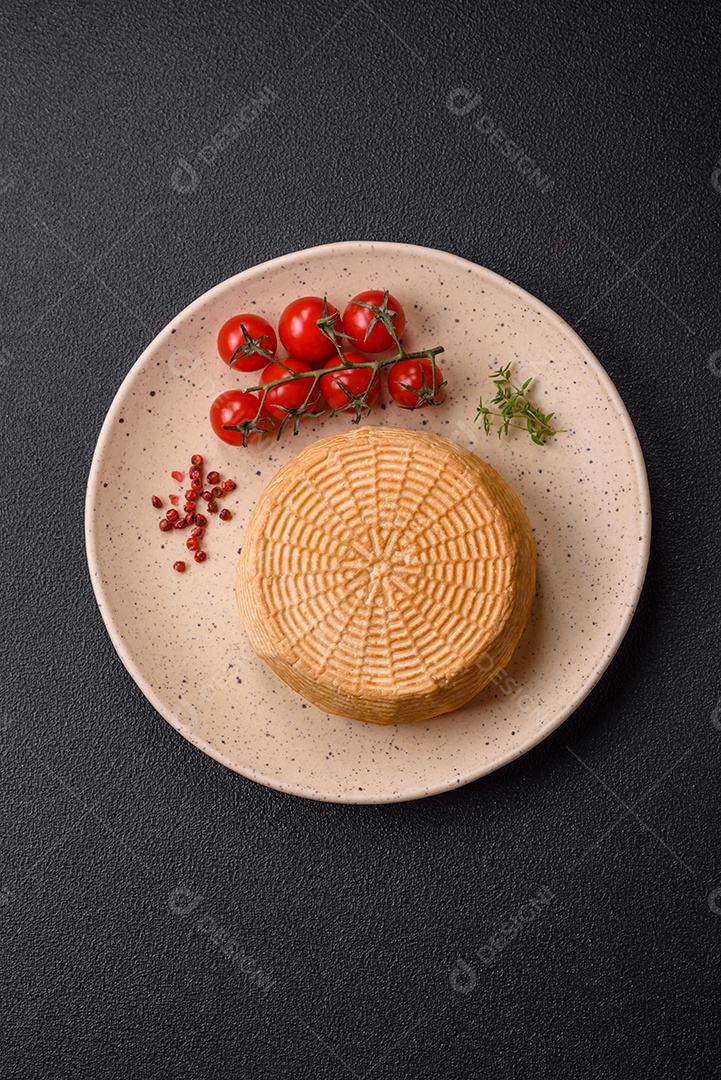 Delicioso queijo artesanal feito de leite de vaca ou cabra sobre um fundo escuro de concreto