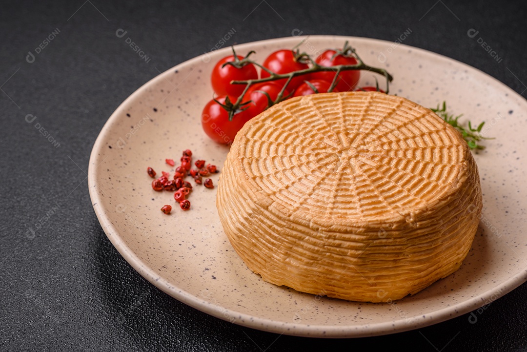 Delicioso queijo artesanal feito de leite de vaca ou cabra sobre um fundo escuro de concreto