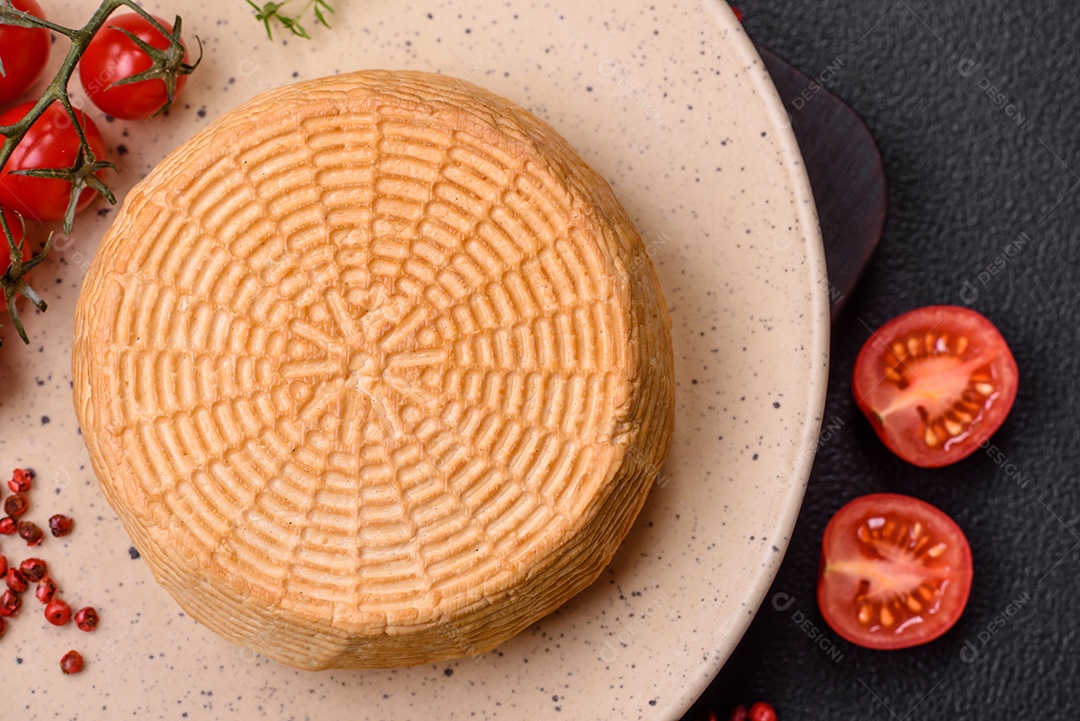 Delicioso queijo artesanal feito de leite de vaca ou cabra sobre um fundo escuro de concreto