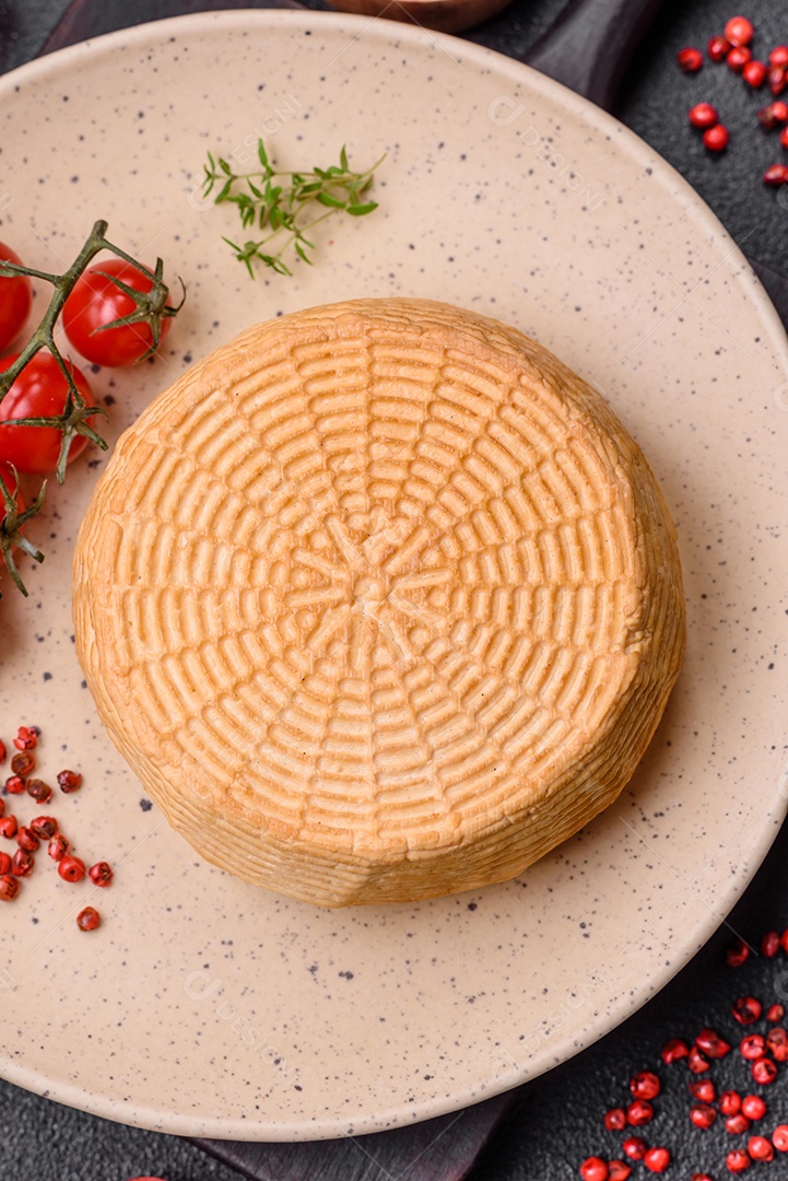 Delicioso queijo artesanal feito de leite de vaca ou cabra sobre um fundo escuro de concreto