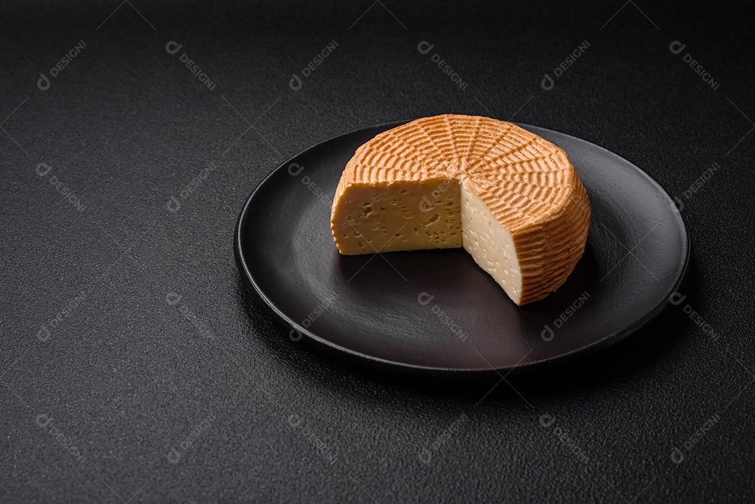 Delicioso queijo artesanal feito de leite de vaca ou cabra sobre um fundo escuro de concreto