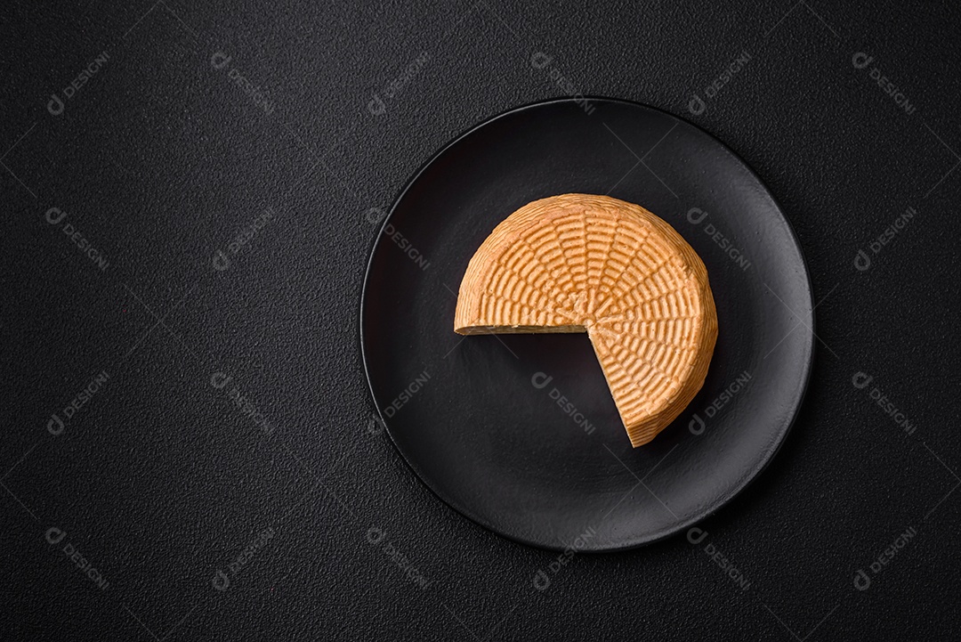 Delicioso queijo artesanal feito de leite de vaca ou cabra sobre um fundo escuro de concreto