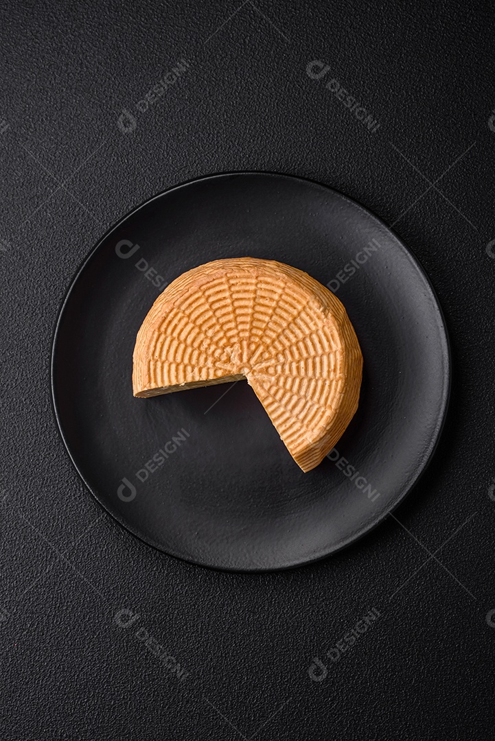 Delicioso queijo artesanal feito de leite de vaca ou cabra sobre um fundo escuro de concreto