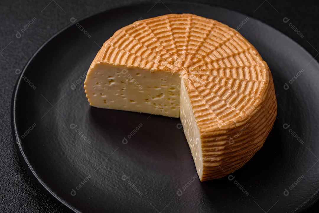 Delicioso queijo artesanal feito de leite de vaca ou cabra sobre um fundo escuro de concreto