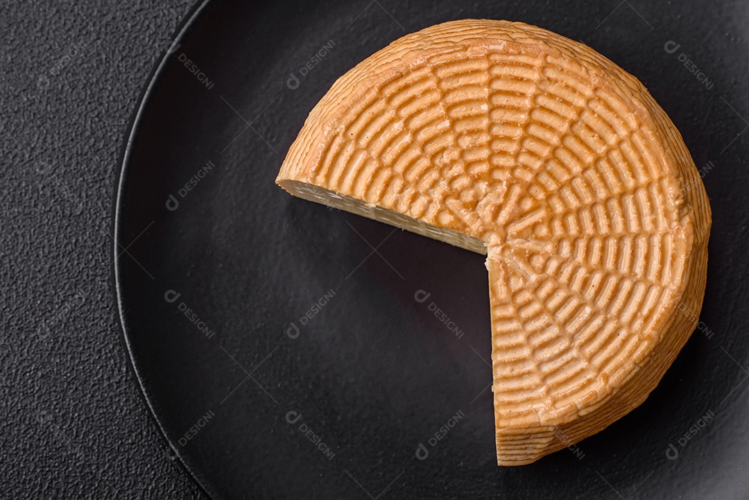 Delicioso queijo artesanal feito de leite de vaca ou cabra sobre um fundo escuro de concreto