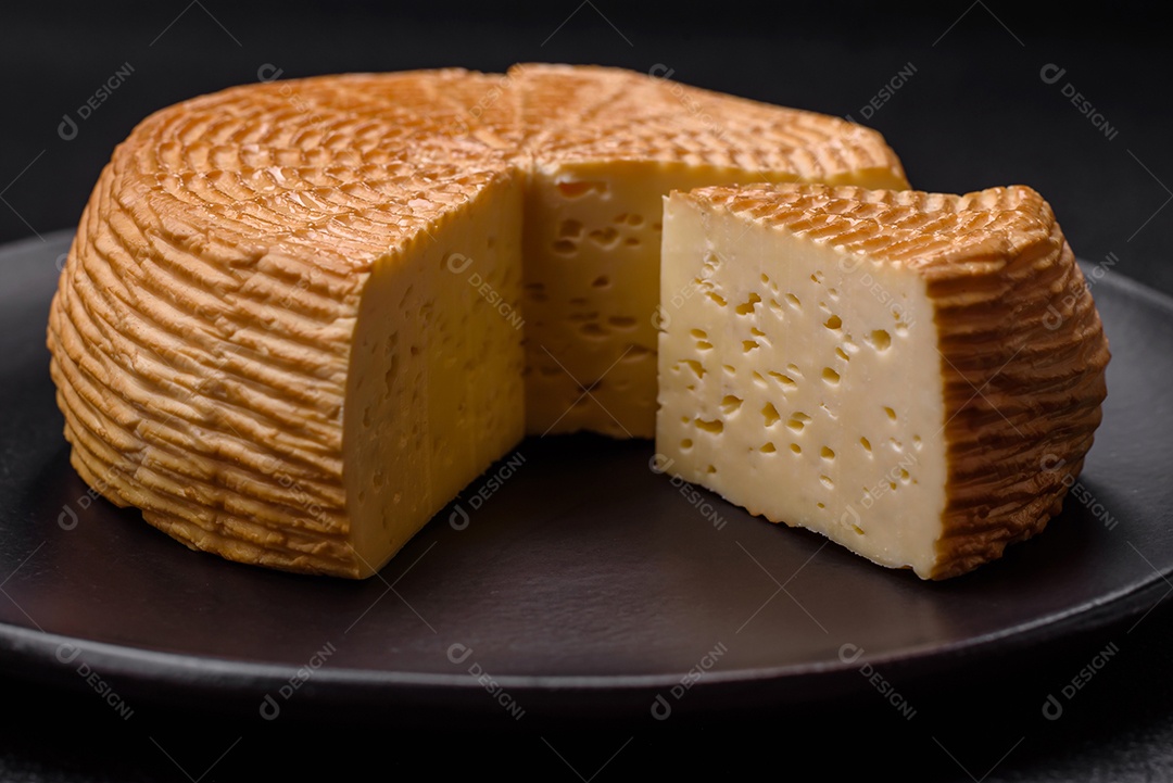 Delicioso queijo artesanal feito de leite de vaca ou cabra sobre um fundo escuro de concreto