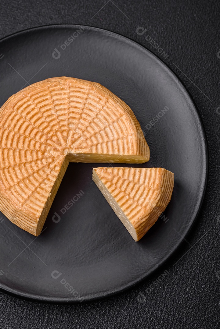 Delicioso queijo artesanal feito de leite de vaca ou cabra sobre um fundo escuro de concreto