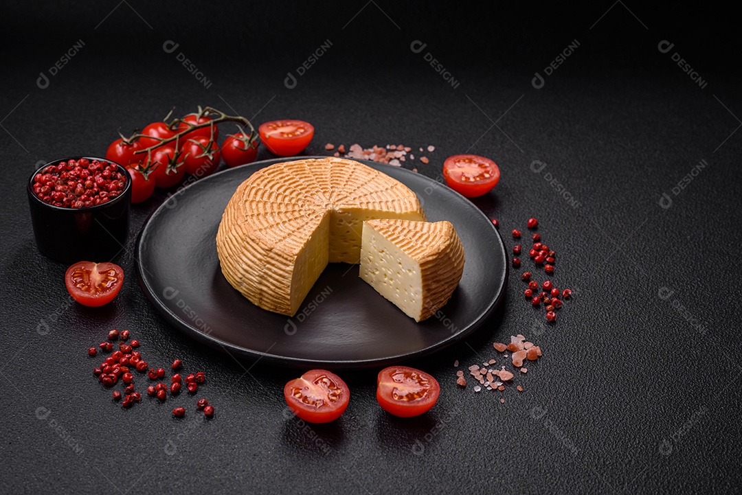 Delicioso queijo artesanal feito de leite de vaca ou cabra sobre um fundo escuro de concreto