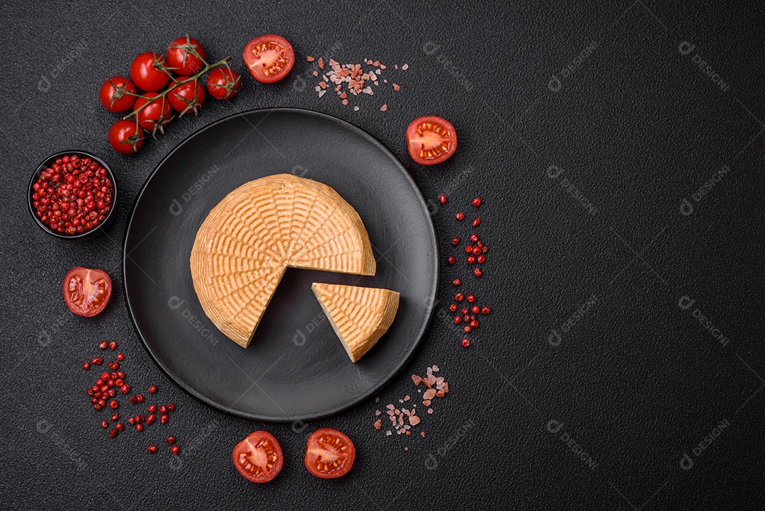 Delicioso queijo artesanal feito de leite de vaca ou cabra sobre um fundo escuro de concreto