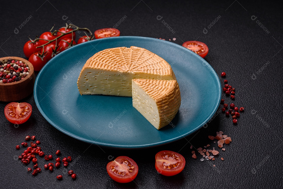 Delicioso queijo artesanal feito de leite de vaca ou cabra sobre um fundo escuro de concreto