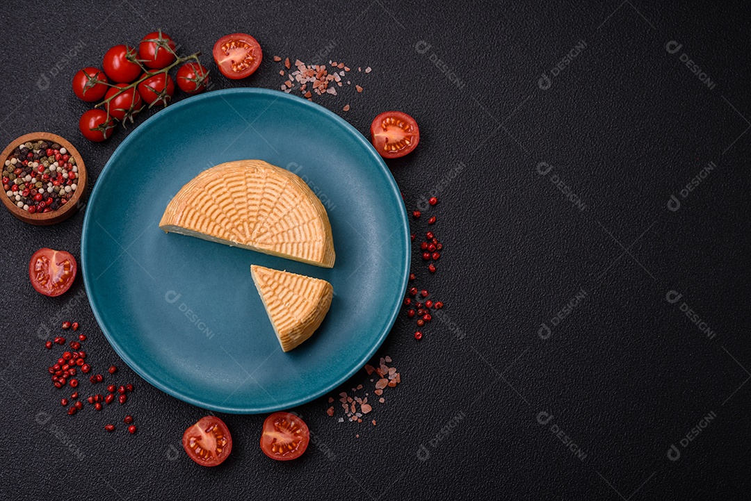 Delicioso queijo artesanal feito de leite de vaca ou cabra sobre um fundo escuro de concreto