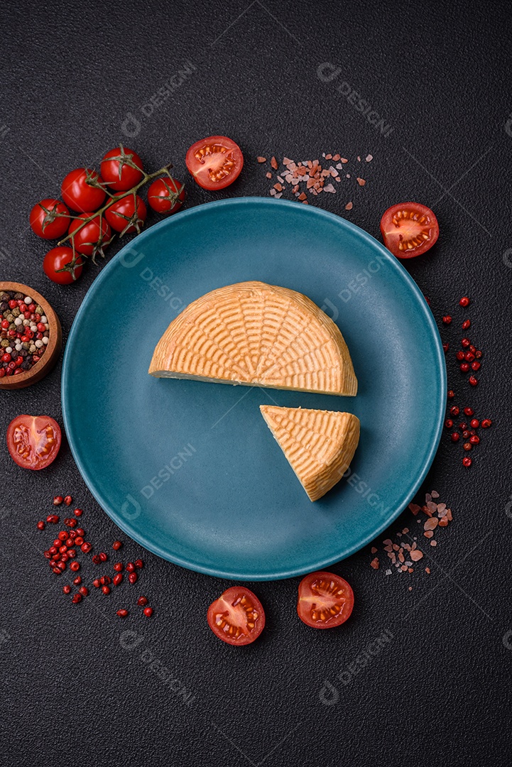 Delicioso queijo artesanal feito de leite de vaca ou cabra sobre um fundo escuro de concreto