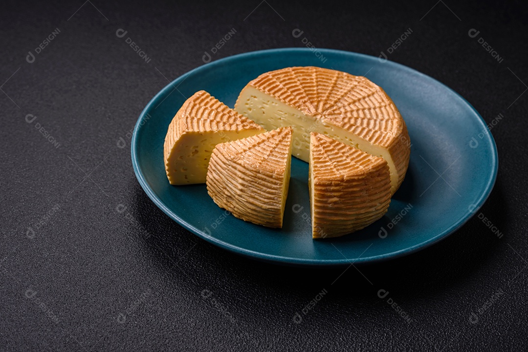 Delicioso queijo artesanal feito de leite de vaca ou cabra sobre um fundo escuro de concreto