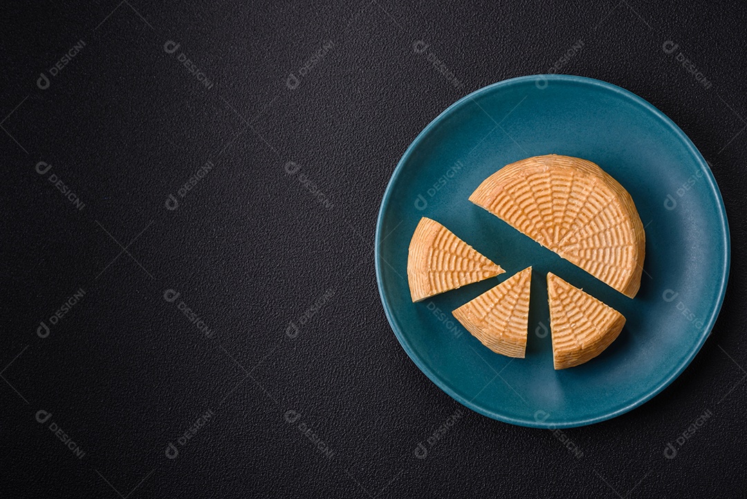 Delicioso queijo artesanal feito de leite de vaca ou cabra sobre um fundo escuro de concreto