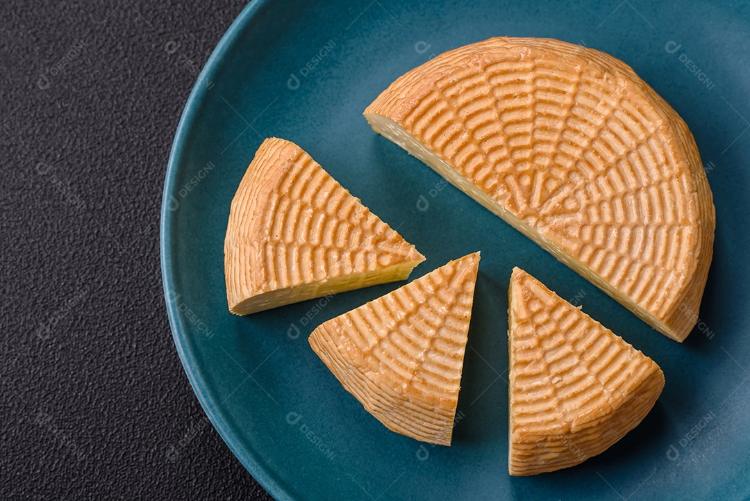 Delicioso queijo artesanal feito de leite de vaca ou cabra sobre um fundo escuro de concreto