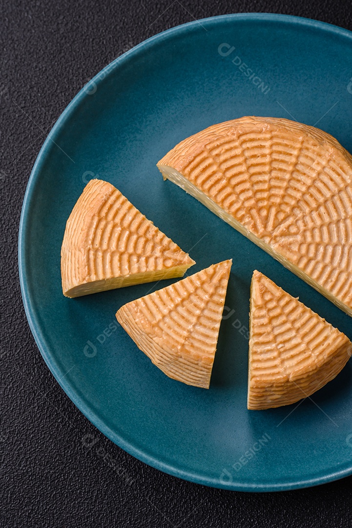 Delicioso queijo artesanal feito de leite de vaca ou cabra sobre um fundo escuro de concreto