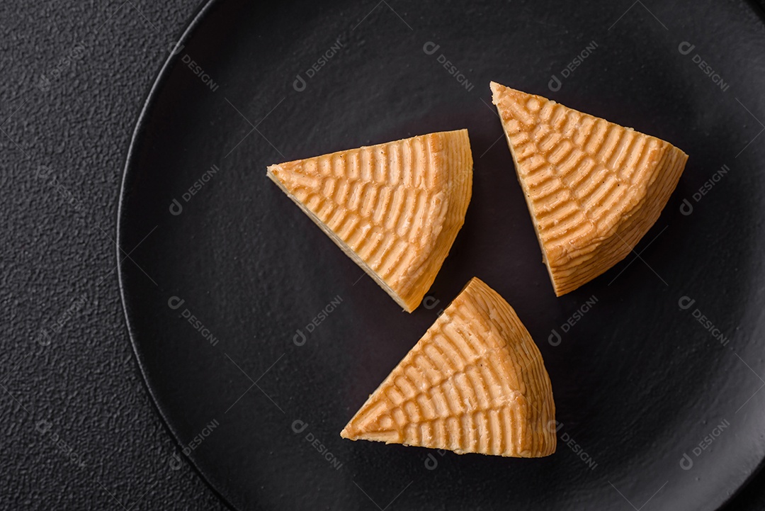 Delicioso queijo artesanal feito de leite de vaca ou cabra sobre um fundo escuro de concreto