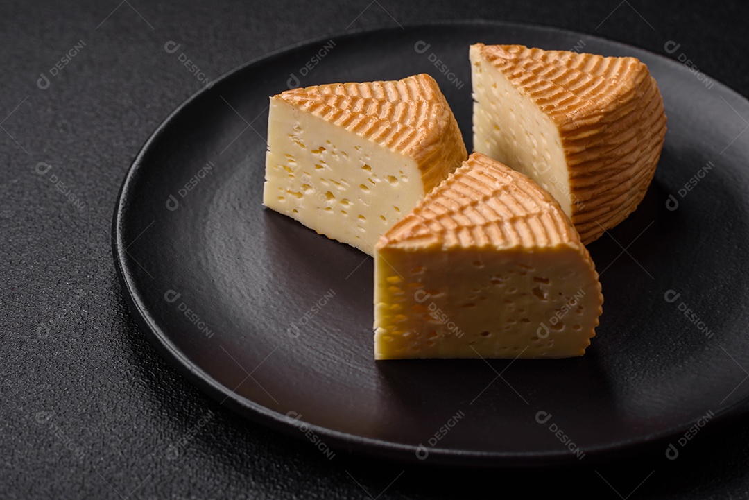 Delicioso queijo artesanal feito de leite de vaca ou cabra sobre um fundo escuro de concreto