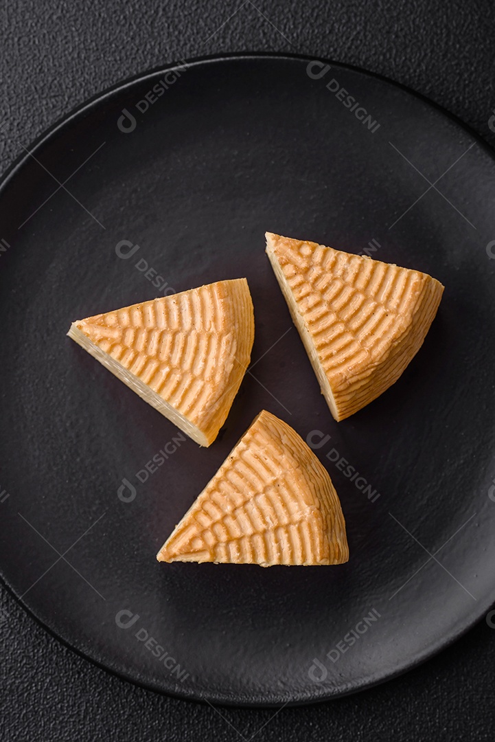 Delicioso queijo artesanal feito de leite de vaca ou cabra sobre um fundo escuro de concreto