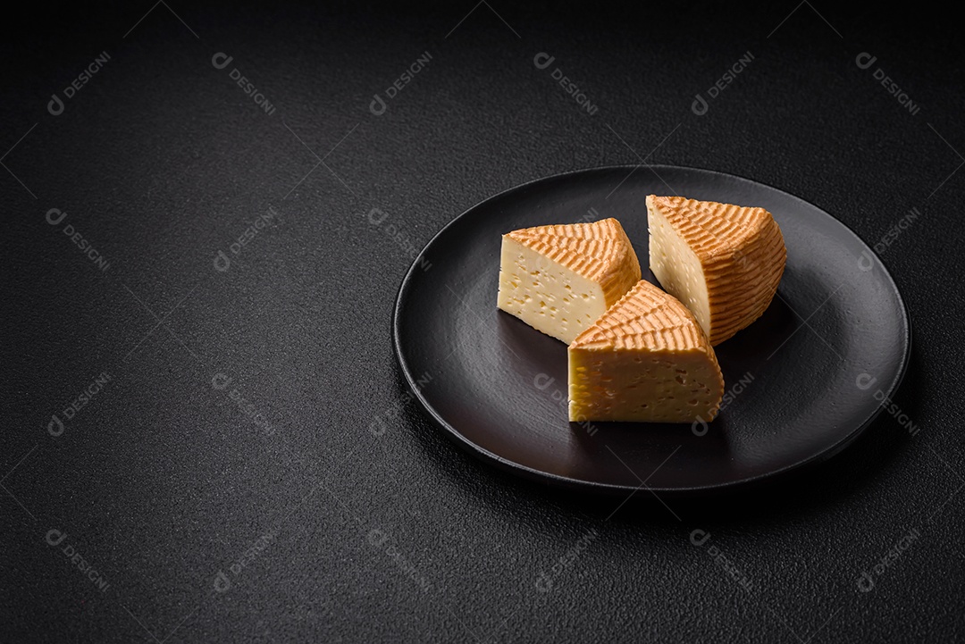 Delicioso queijo artesanal feito de leite de vaca ou cabra sobre um fundo escuro de concreto