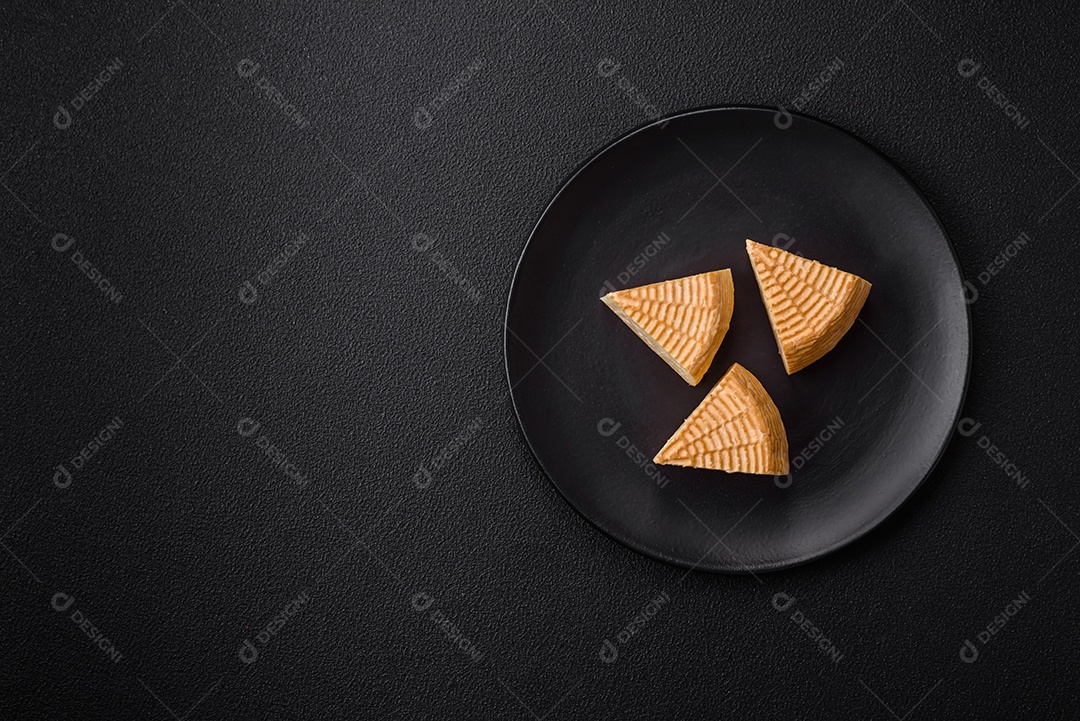 Delicioso queijo artesanal feito de leite de vaca ou cabra sobre um fundo escuro de concreto