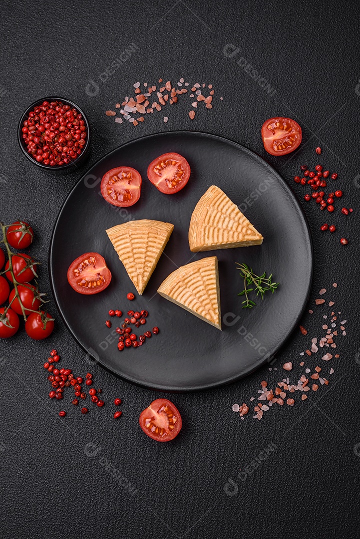 Delicioso queijo artesanal feito de leite de vaca ou cabra sobre um fundo escuro de concreto
