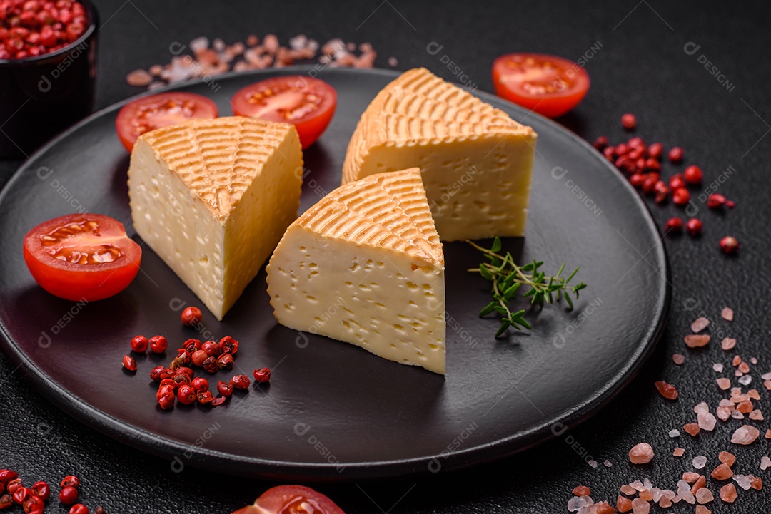 Delicioso queijo artesanal feito de leite de vaca ou cabra sobre um fundo escuro de concreto