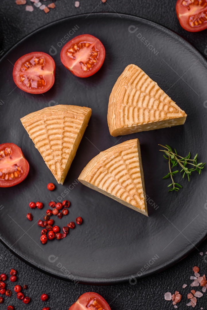 Delicioso queijo artesanal feito de leite de vaca ou cabra sobre um fundo escuro de concreto